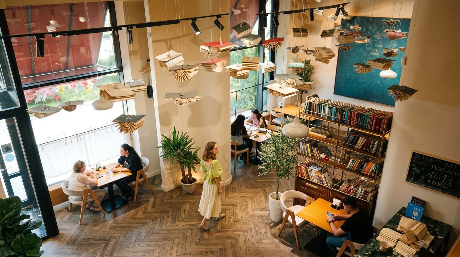 Зал Bookish Cafe сверху: столы, книжные полки и книги под потолком